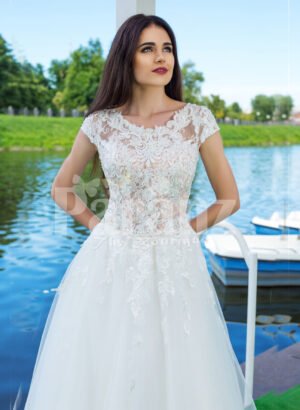 Elegant pearl white floor length flared tulle skirt wedding gown with lacy bodice close view