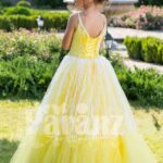Light yellow sleeveless baby gown with rhinestone neckline and floor length tulle skirt back side view