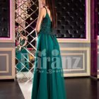 Woman’s stylish deep green evening gown with side slit tulle skirt and rich rhinestone bodice back side view