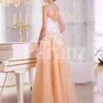 Women’s glam evening gown with peachy orange flared tulle skirt and appliquéd white bodice side view