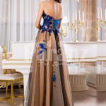 Women’s off-shoulder long tulle evening gown with bright blue floral appliquéd bodice back side view
