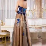 Women’s off-shoulder long tulle evening gown with bright blue floral appliquéd bodice back side view