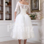 Women’s tea length white lacy bodice and tulle skirt wedding gown back side view