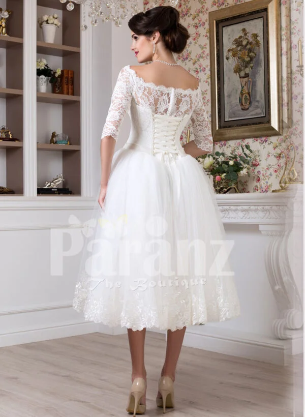 Women’s tea length white lacy bodice and tulle skirt wedding gown back side view